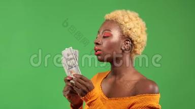 一位有着金钱狂热的非裔美国妇女挥舞着金钱，在一片孤立的绿色上以一种愉快的表情驱散了金钱